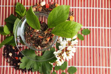 Cam bardak çay, bambu Hasır arka plan için kuru çiçekler ve bitkiler malzemelerle