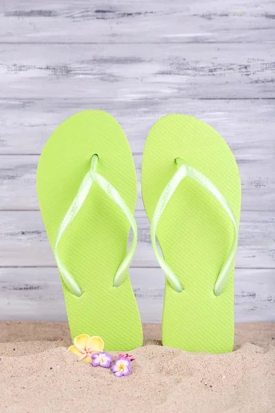 Heldere slippers op zand, op houten achtergrond — Stockfoto