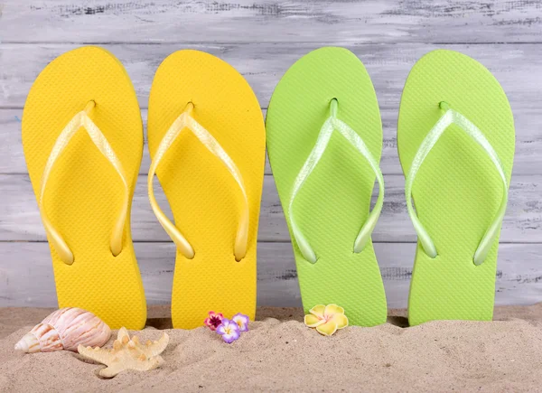 Bright flip-flops on sand, on wooden background — Stock Photo, Image