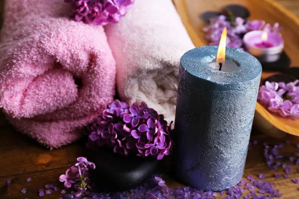 Composición con tratamiento spa, cuenco de madera con agua, toalla y flores lila, sobre fondo de madera —  Fotos de Stock