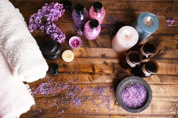 Composition with spa treatment, towels and lilac flowers, on wooden background — Stock Photo, Image