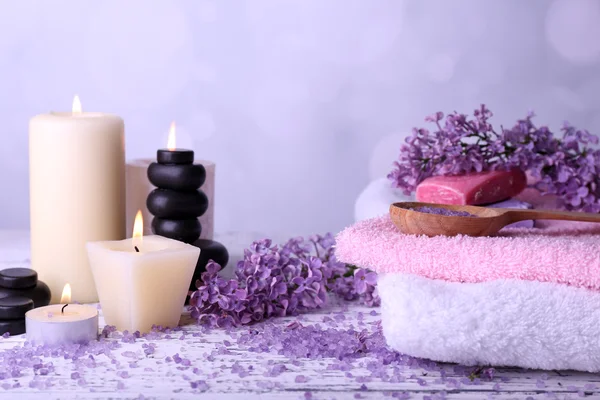 Sammansättning med spa behandling, handdukar och lila blommor, på ljus bakgrund — Stockfoto