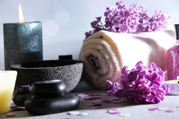 Composition with spa treatment, towels and lilac flowers, on wooden table, on light background — Stock Photo, Image