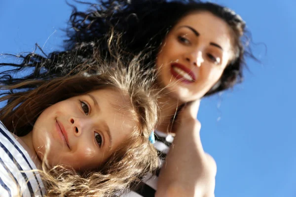 Feliz mamá y su hija en el fondo del cielo azul — Foto de Stock