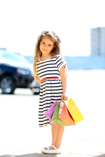Glückliches kleines Mädchen mit Einkaufstaschen, im Freien — Stockfoto