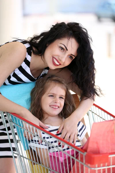 Mãe feliz e filha com sacos de loja, ao ar livre — Fotografia de Stock