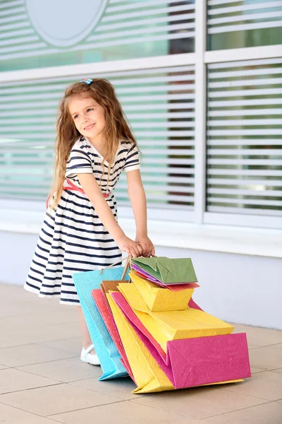 Glad liten flicka med shop väskor, utomhus — Stockfoto