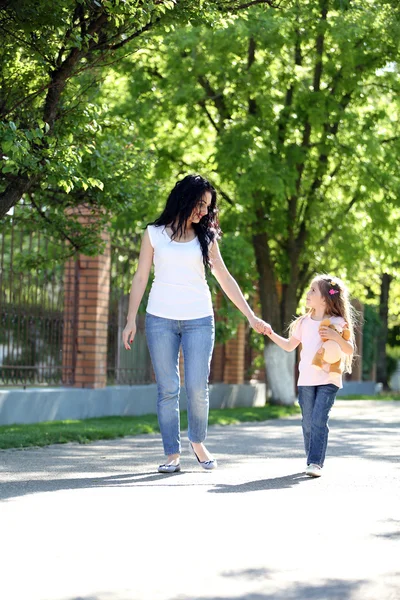 幸せな母と娘。緑豊かな公園の中を歩く — ストック写真