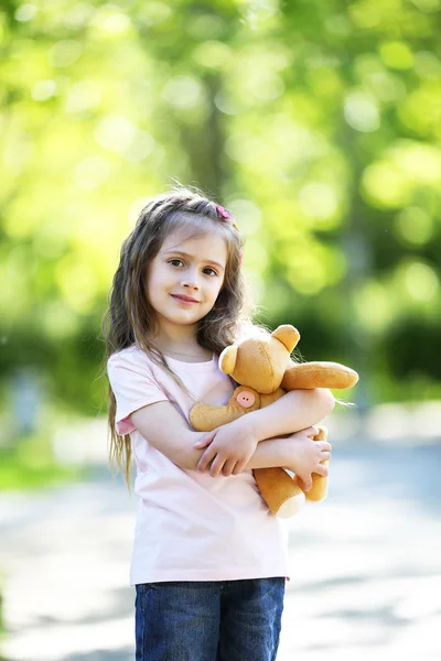 Happy little girl with toy bear in the green park — Stock Photo, Image