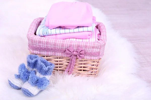 Baby clothes in basket on floor in room — Stock Photo, Image