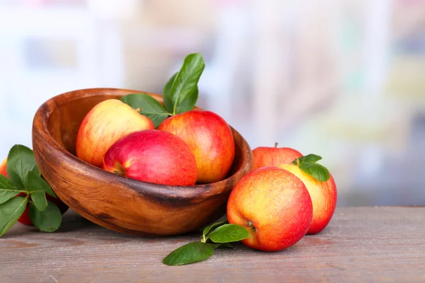 成熟甜的苹果木碗里在明亮的背景上的叶子 — 图库照片