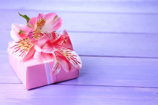 Presente rosa com arco e flor na mesa de madeira close-up — Fotografia de Stock