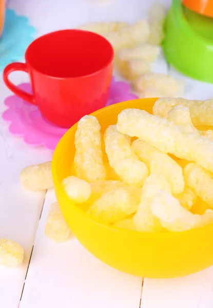 Air corn sticks in bowl on wooden table surrounded by toys close-up — Stock Photo, Image