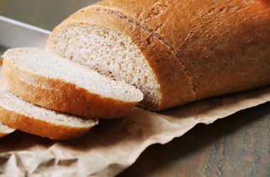 Ahşap tahtada ekmek kesen kadın elleri, yakın plan.