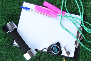 Sheet of paper and sports equipment on grass close-up clipart
