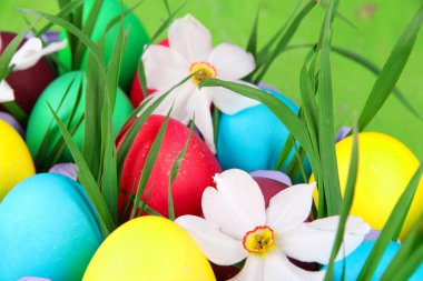 çim ve çiçek içinde tepsi ahşap arka plan üzerinde renkli Paskalya yumurtaları