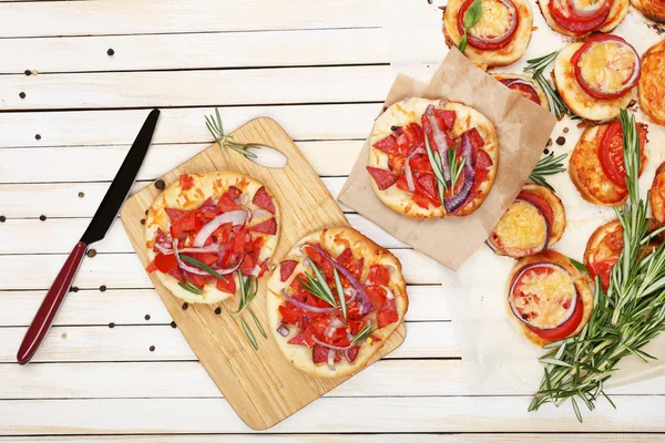 Small pizzas on baking paper close up — Stock Photo, Image