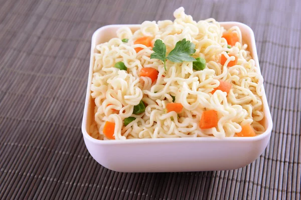 Sabrosos fideos instantáneos con verduras en un tazón en la mesa de cerca —  Fotos de Stock