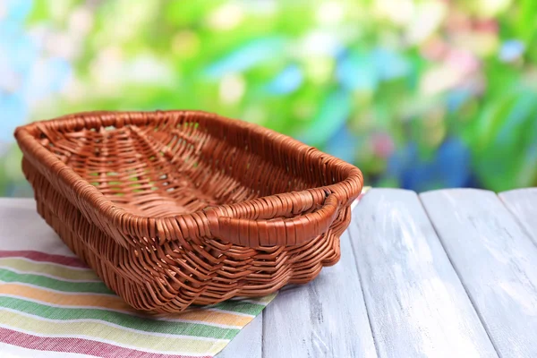 Leerer Weidenkorb auf Holztisch, auf hellem Hintergrund — Stockfoto