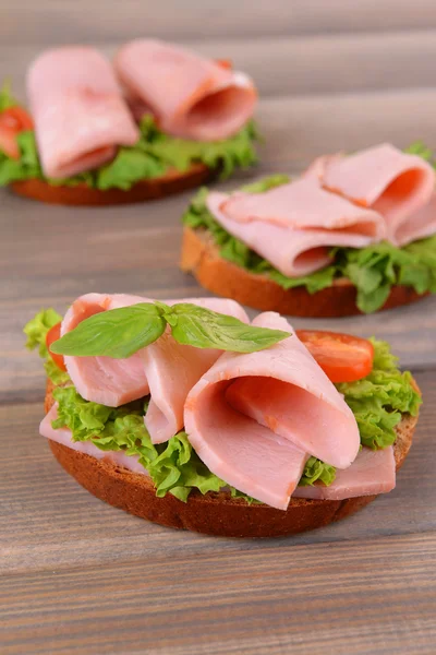 Вкусные бутерброды с салатом и ветчиной на столе крупным планом — стоковое фото
