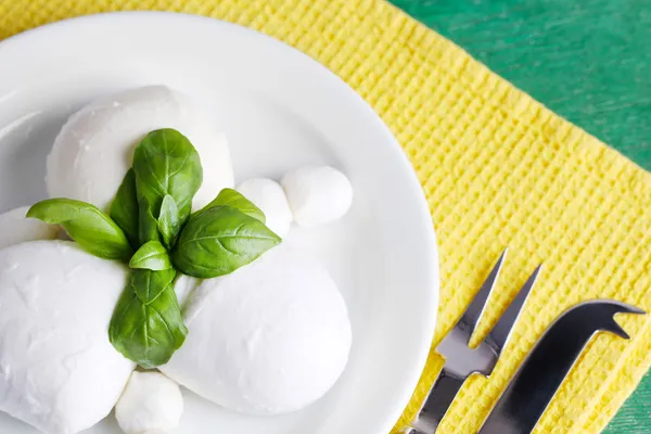 Gustosa mozzarella con basilico su piatto su fondo di legno — Foto Stock