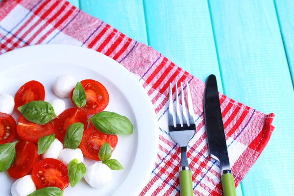 Ensalada Caprese con queso mozarella, tomates y albahaca en plato, sobre fondo de mesa de madera — Foto de Stock