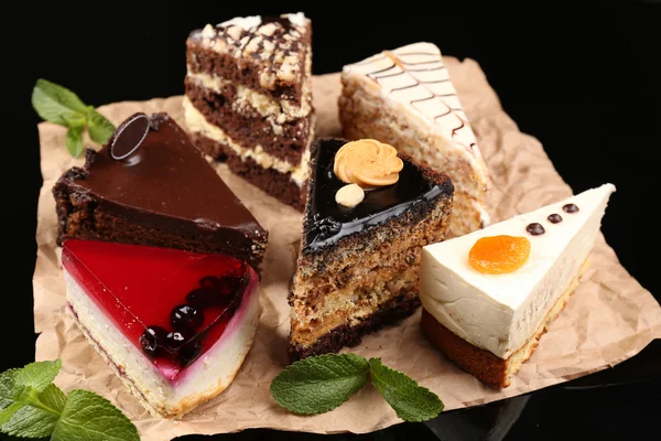 Assortiment van stukken van cake, op donkere achtergrond — Stockfoto