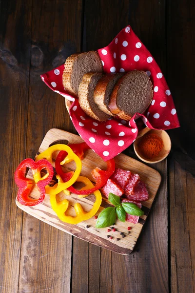 Sammansättning med kniv, välsmakande salami korv, skivat bröd och peppar på skärbräda, på trä bakgrund — Stockfoto