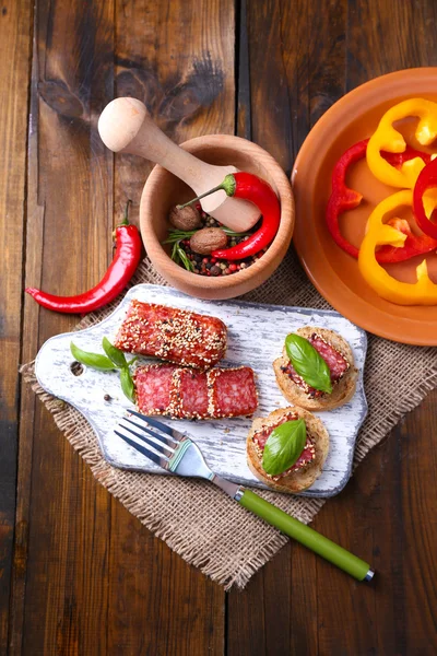 Bıçak, salam sosis ile lezzetli sandviçler, ahşap zemin üzerinde kesme tahtası fesleğen yaprağı ile kompozisyon — Stok fotoğraf