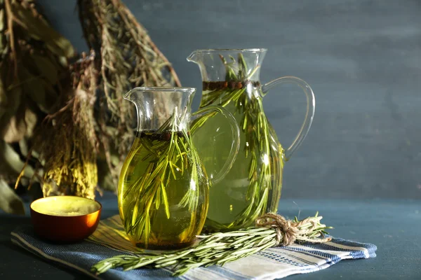 Olio essenziale con rosmarino in brocche di vetro, su fondo di legno — Foto Stock