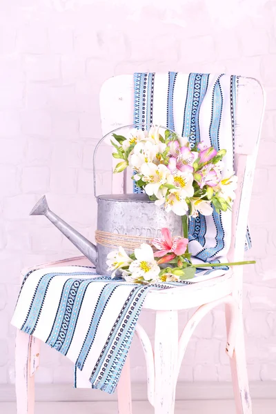 Piękny bukiet z frezji w konewka na krześle w pokoju — Zdjęcie stockowe