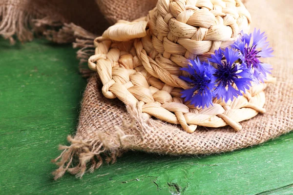 Cappello piccolo in paglia con fiordaliso su fondo legno — Foto Stock