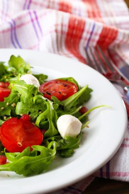 roka, domates, peynir mozzarella toplar ve ahşap zemin üzerinde plaka üzerinde susam ile yapılan yeşil salata