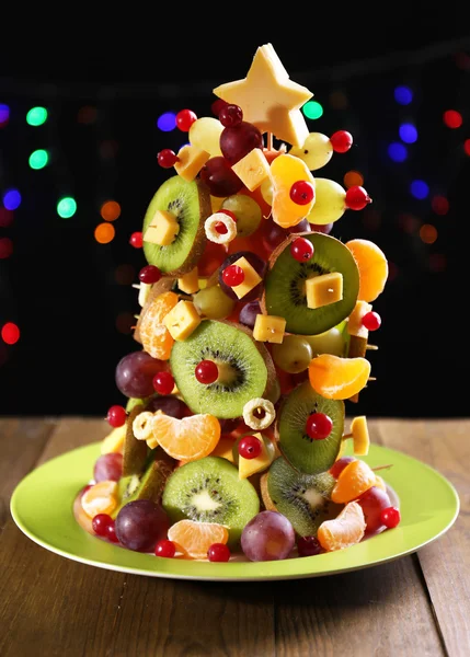 Árbol de Navidad de frutas en la mesa sobre fondo oscuro —  Fotos de Stock