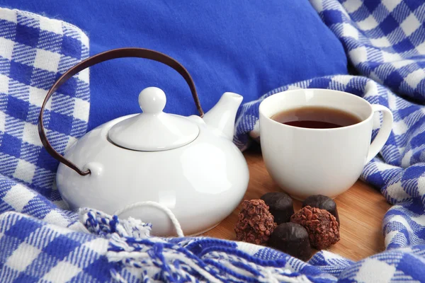 Tasse und Teekanne mit Bonbons auf Holzständer auf dem Bett aus nächster Nähe — Stockfoto