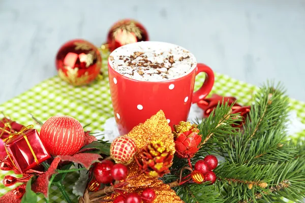 Горячий шоколад со сливками в цветной кружке, на салфетке, на фоне рождественских украшений — стоковое фото
