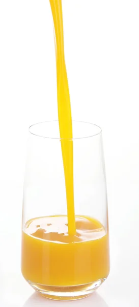 Сік наливається в склянку ізольовано на білому — стокове фото