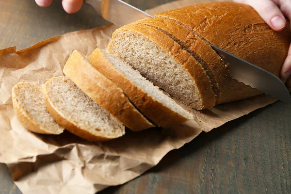 Female hands cutting bread on wooden board, close-up — Stock Photo, Image