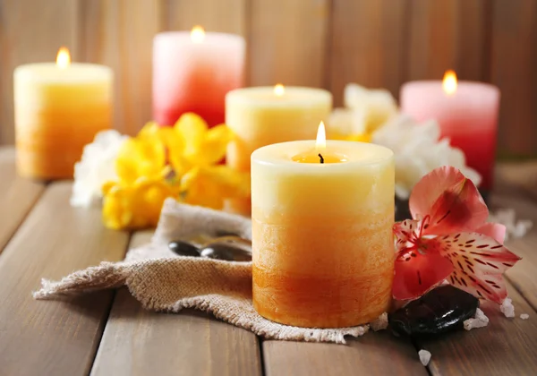 Hermosas velas con flores sobre fondo de madera — Foto de Stock