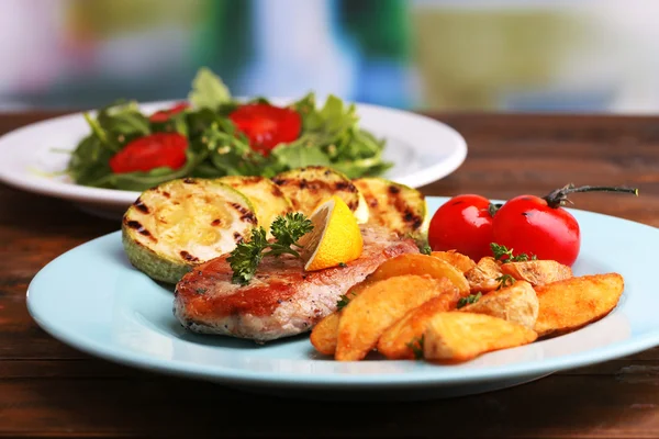 Filete a la parrilla, verduras a la parrilla y ensalada verde fresca en la mesa, sobre un fondo brillante — Foto de Stock