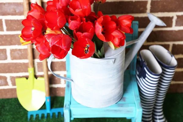 Composition of colorful tulips in watering can and rain boots on bright background — Stock Photo, Image