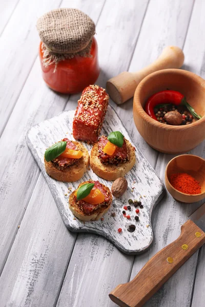 Messerkomposition, leckere Sandwiches mit Salamiwurst, Basilikumblatt auf Schneidebrett, auf Holzgrund — Stockfoto