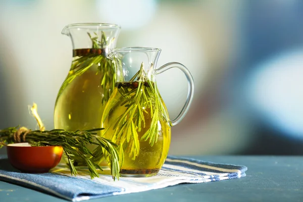 Olio essenziale con rosmarino in brocche di vetro, su tavolo di legno, su fondo brillante — Foto Stock