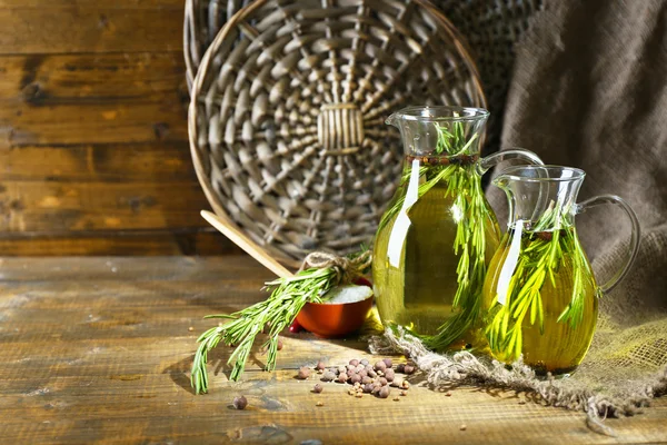 Essential Oil with rosemary in glass jugs, on wooden background — Stock Photo, Image