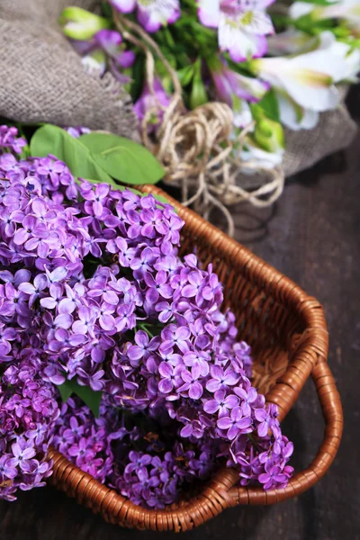 Lindas flores lilás em cesta de vime no fundo de madeira — Fotografia de Stock
