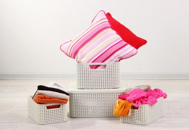 Plastic baskets with things in floor on room background clipart