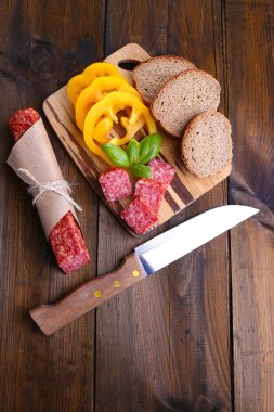 zboczeniecbıçak, lezzetli salam sosis, dilimlenmiş ekmek ve ahşap zemin üzerinde kesme tahtası üzerinde biber ile kompozisyon