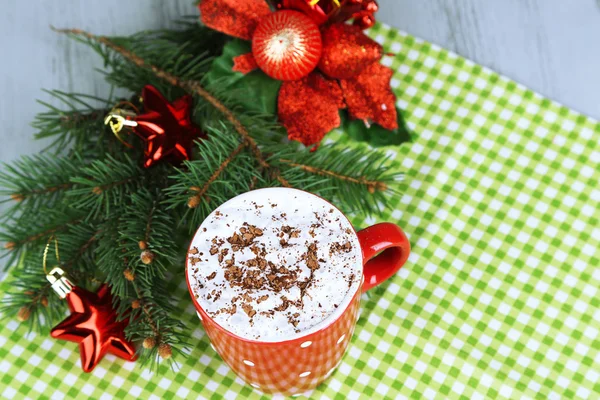 Cioccolata calda con crema in tazza di colore, su tovagliolo, su sfondo decorazioni natalizie — Foto Stock