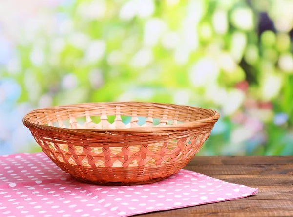 Cesta de mimbre vacía sobre mesa de madera, sobre fondo brillante —  Fotos de Stock