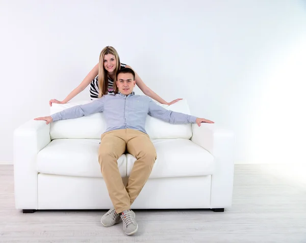 Loving couple sitting on sofa, on light background — Stock Photo, Image